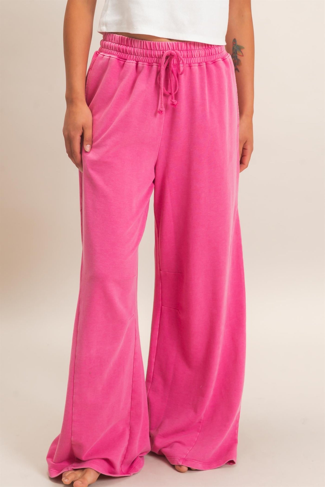 woman wearing pink wide-leg lounge pants with an elastic waistband and drawstring detail