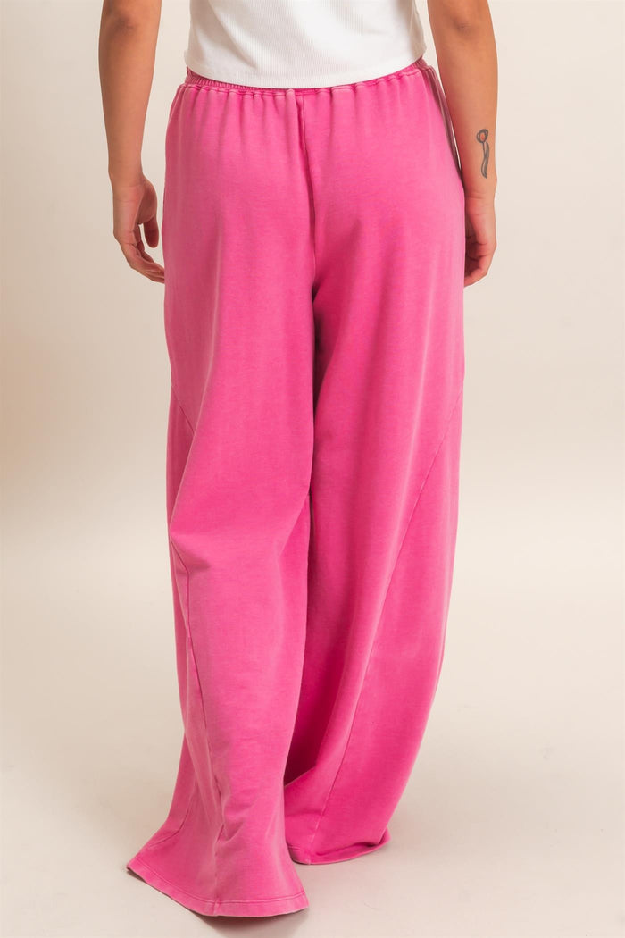 woman wearing loose-fitting bright pink lounge pants with an elastic waistband, viewed from the back