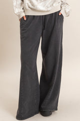 woman wearing dark gray wide-leg lounge pants with side pockets and a relaxed fit