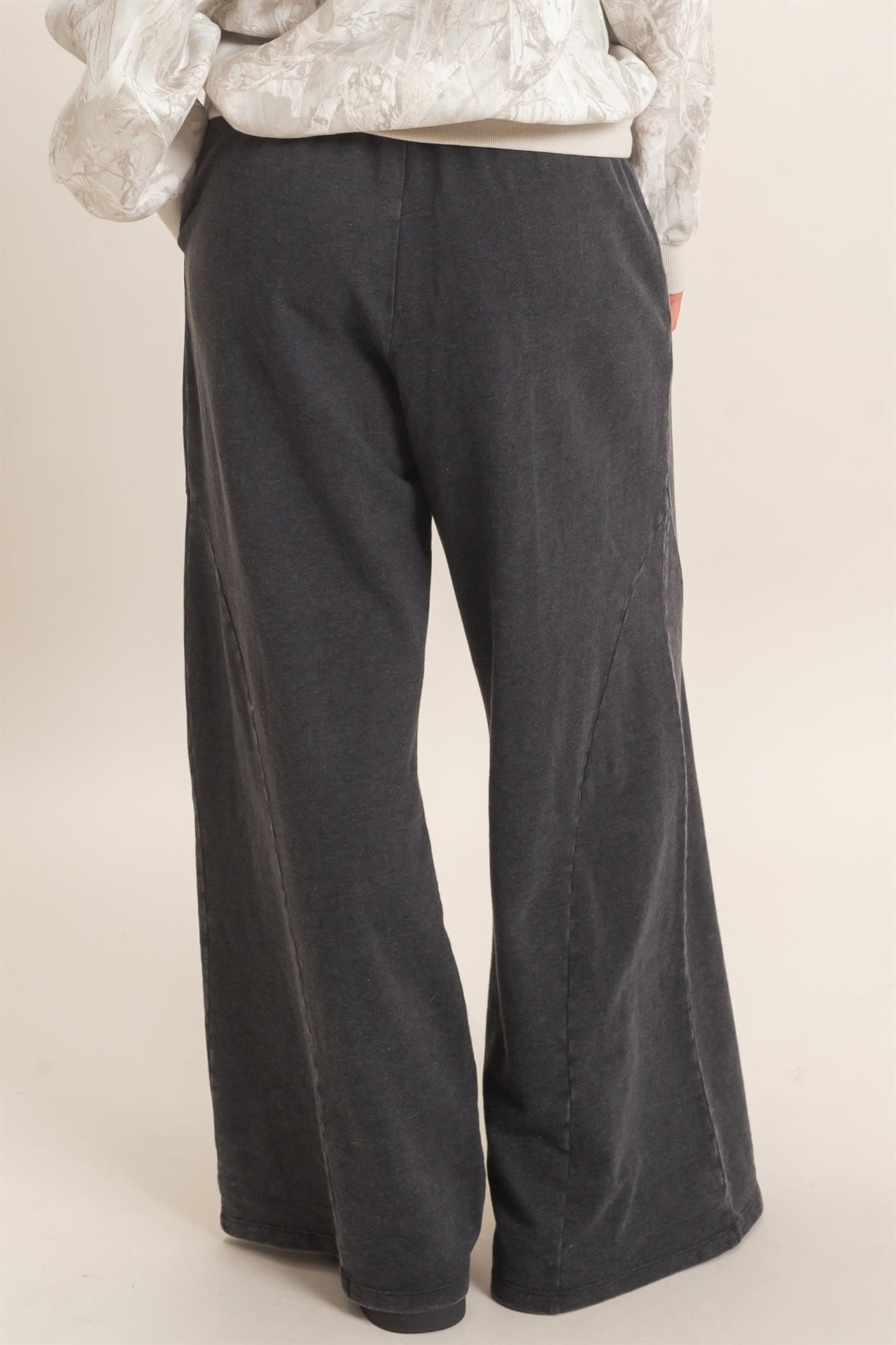 woman wearing dark gray wide-leg pants with side seam details, view from the back