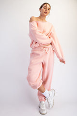 woman wearing a light pink oversized sweatshirt and matching joggers, styled casually with white sneakers