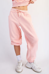 woman wearing pink cropped sweatpants with pockets and an elastic waistband, paired with white sneakers
