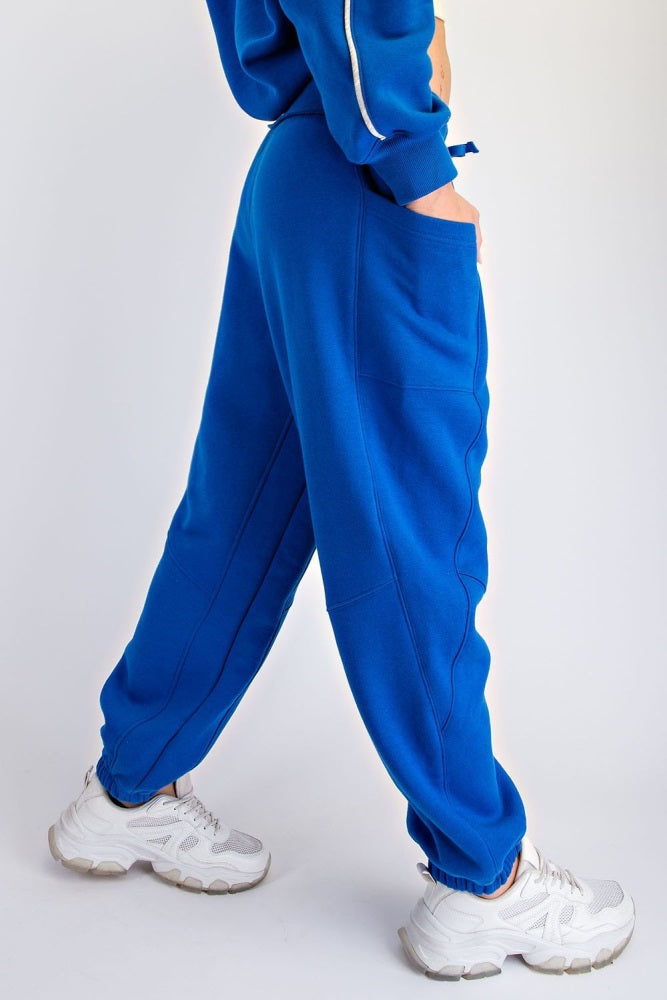 woman wearing a pair of vibrant blue sweatpants with side pockets and a loose fit, paired with white sneakers