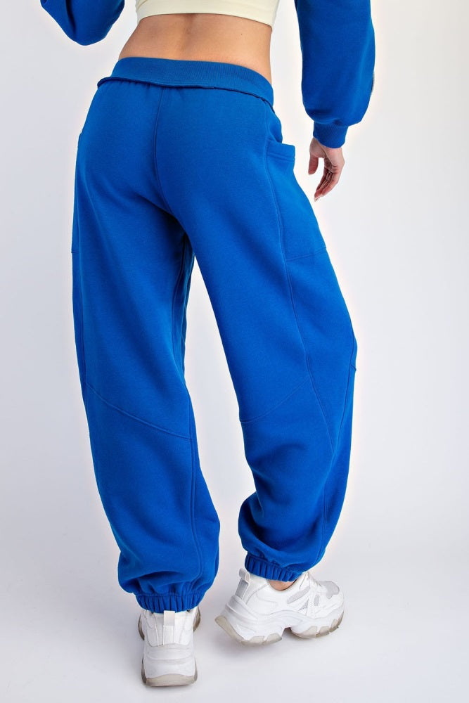 woman wearing bright blue oversized sweatpants with elastic cuffs and pockets, view from the back