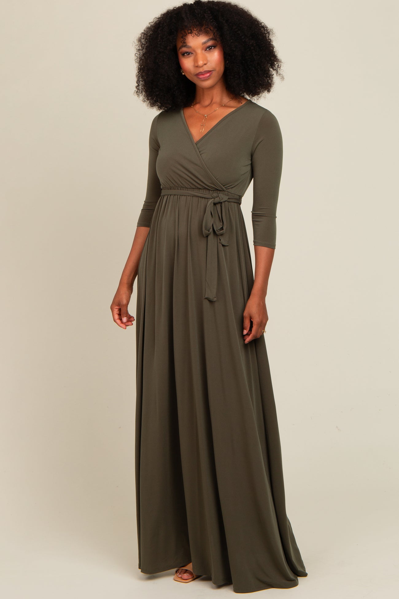 woman wearing an olive green long sleeve wrap dress with a tie waist and flowing skirt