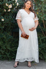 woman wearing a white lace maternity maxi dress and holding her baby bump with a small clutch bag