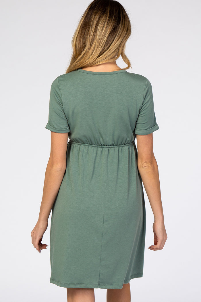woman wearing a green short sleeve maternity dress with an elastic waistband and a relaxed fit