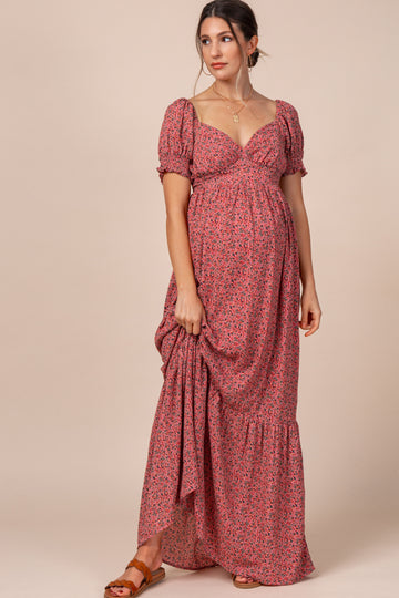 woman wearing a pink floral maternity maxi dress with puff sleeves and a gathered waist, showcasing her baby bump