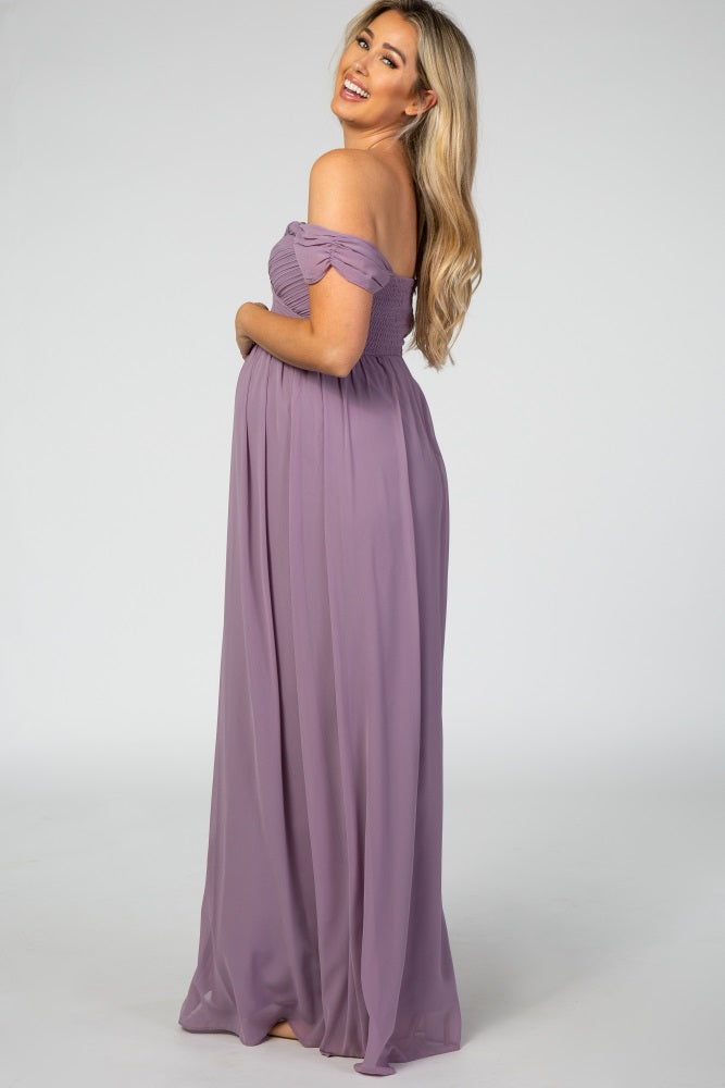 woman wearing a light purple off-the-shoulder maternity dress with a flowing skirt and showing her baby bump