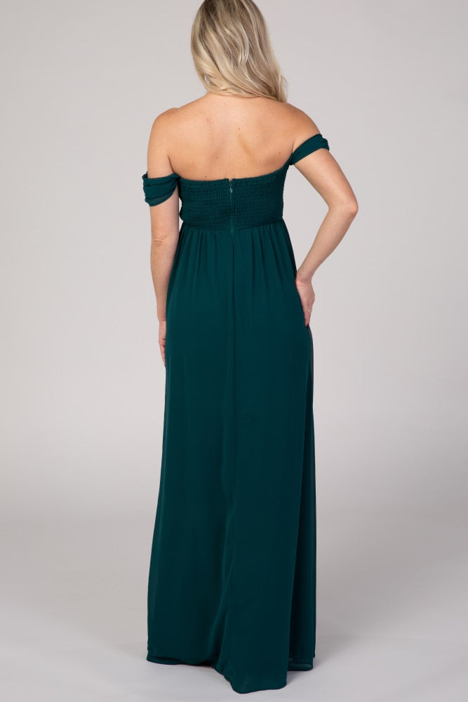 woman wearing a dark green off-the-shoulder maternity maxi dress with a smocked bodice and a flowing skirt