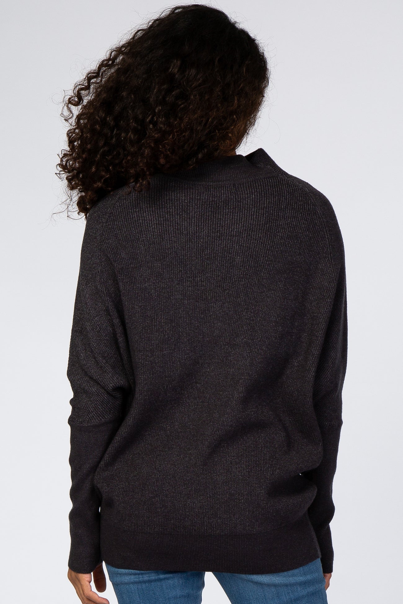woman wearing a dark gray oversized sweater with a relaxed fit and open back, viewed from the back