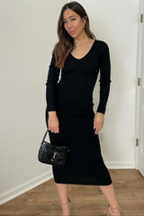 woman wearing a black ribbed long sleeve dress and holding a small handbag