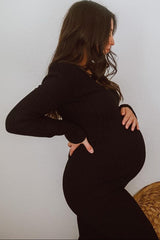 woman wearing a black ribbed maternity dress, featuring a fitted silhouette and cradling her baby bump