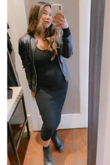 woman wearing a black ribbed maternity dress and a black leather jacket, showing her baby bump in a mirror selfie