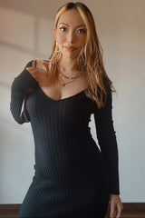 woman wearing a black ribbed long sleeve dress with a deep v-neckline and styled with accessories