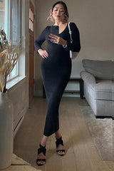 woman wearing a black ribbed long sleeve fitted dress and high heels, posing in a bright room with a plant