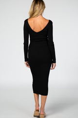 woman wearing a black ribbed maternity dress with a deep V-back and long sleeves, showcasing a fitted silhouette