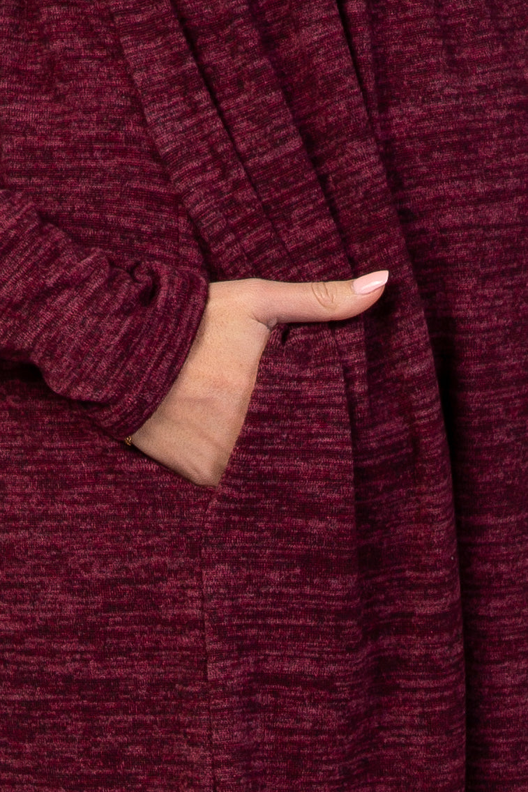 maternity wear in a maroon textured cardigan with pockets and open front, model's hand tucked in the pocket