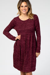 woman wearing a burgundy long sleeve dress with a fitted bodice and a flared skirt