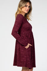 woman wearing a burgundy long sleeve dress with a flared skirt and pockets