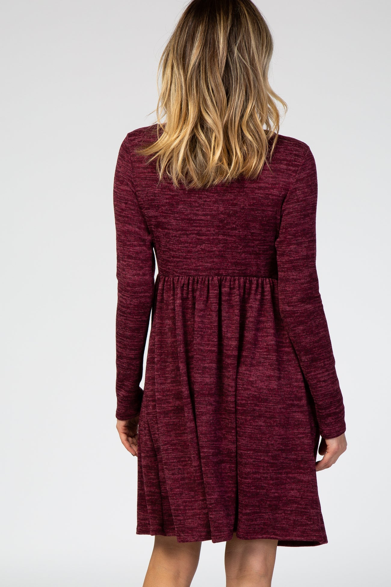 woman wearing a maroon long sleeve skater dress with a fitted bodice and flared skirt