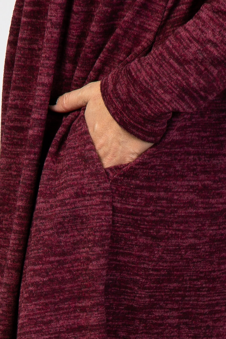 close-up of a hand in the pocket of a burgundy long sleeve knit dress with a comfortable, relaxed fit