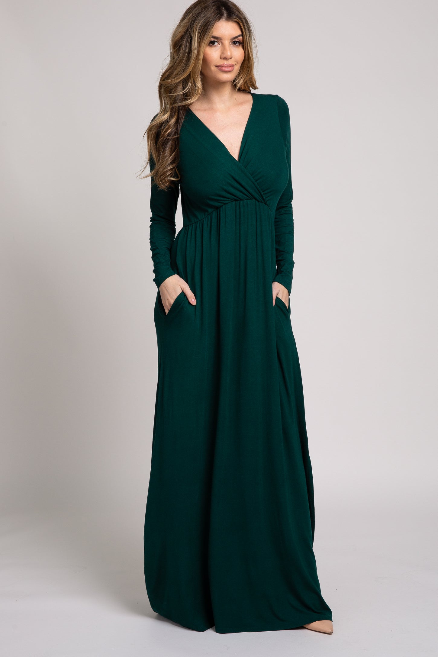 woman wearing a deep green long sleeve maxi dress with pockets and a v-neckline
