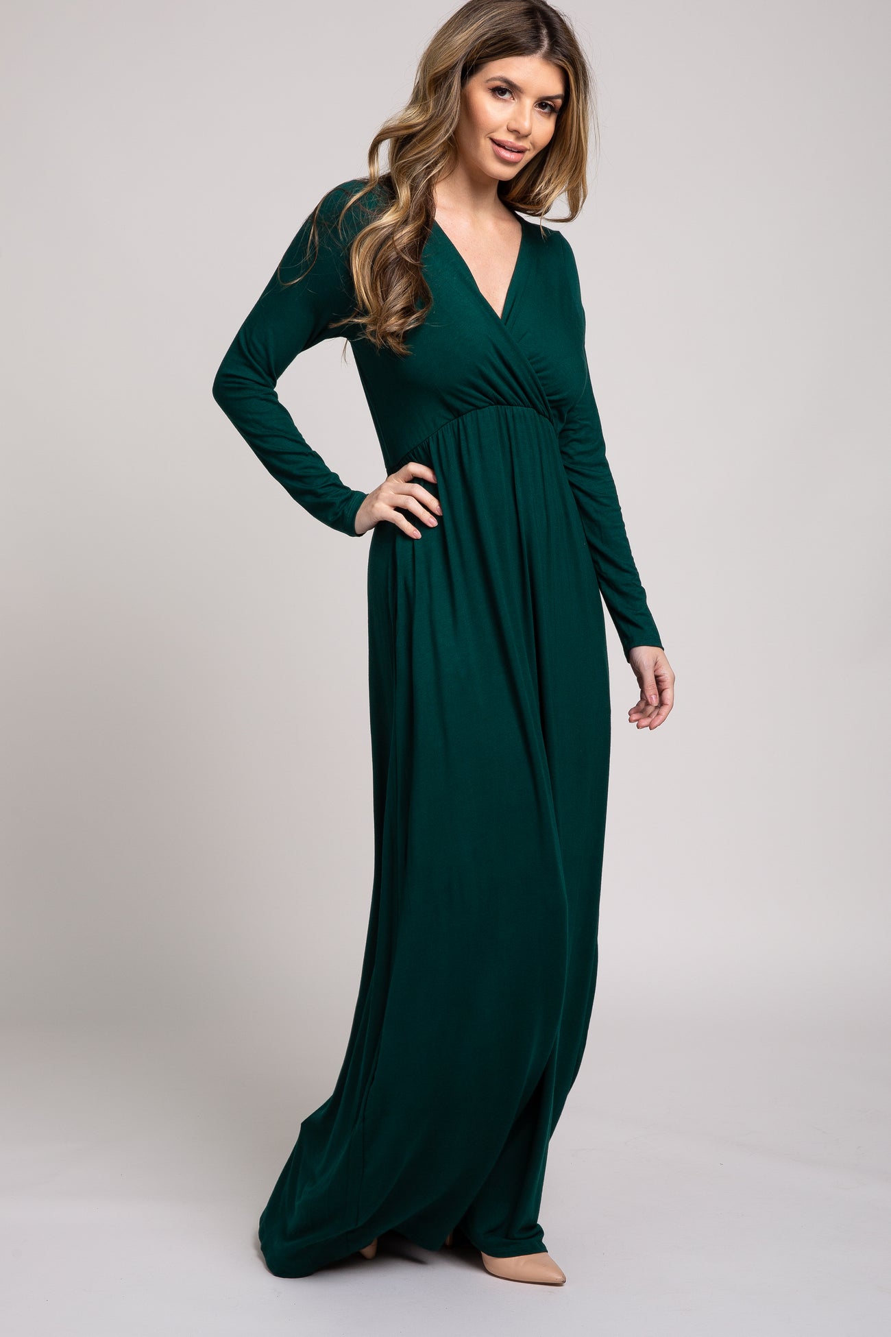 woman wearing a long sleeve dark green v-neck maxi dress with a pleated waist