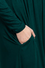 close-up of a woman's hand in the pocket of a dark green long sleeve dress