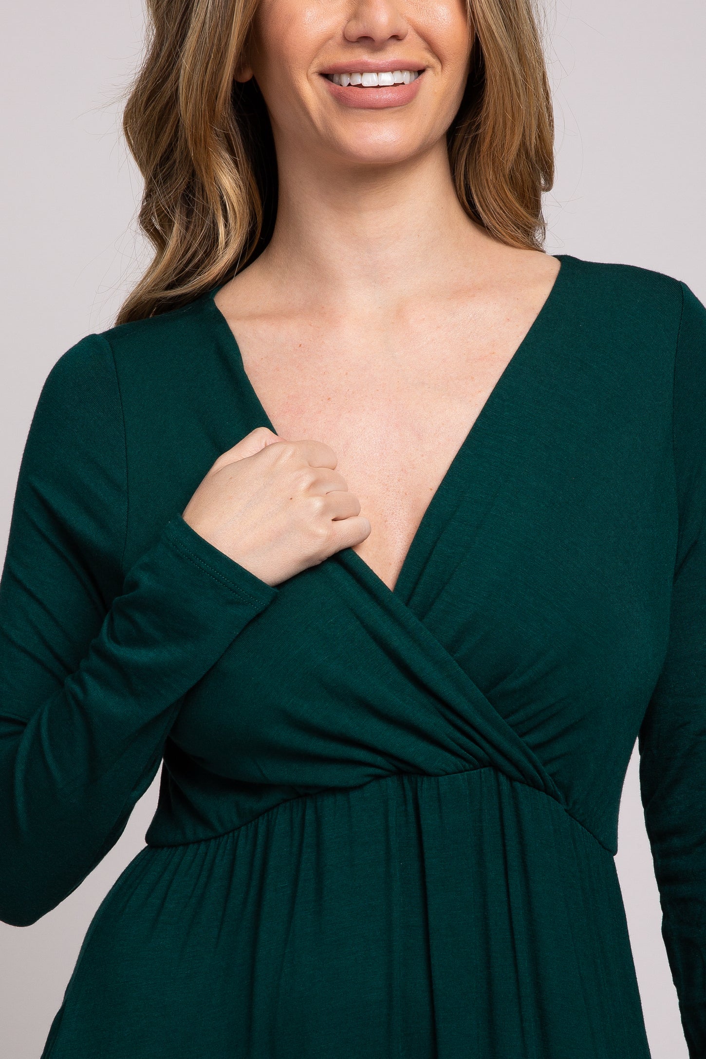 woman wearing a forest green long sleeve wrap dress with a deep v-neck and empire waist detailing