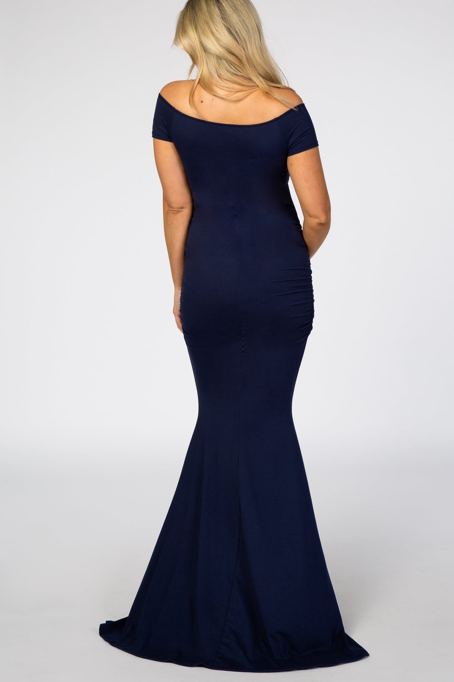 woman wearing a navy blue off-the-shoulder maternity dress with ruched sides, showcasing a baby bump from the back