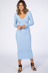 woman wearing a light blue long sleeve ribbed midi dress with a v-neckline and black strappy heels