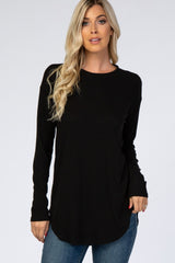 woman wearing a black long sleeve waffle knit top with a curved hem and relaxed fit, paired with blue jeans