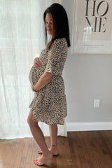 woman wearing a short sleeve beige leopard print maternity dress and showing her baby bump