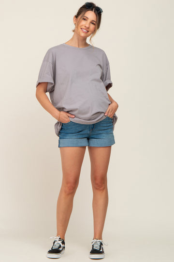 woman wearing a light gray oversized maternity t-shirt and denim shorts with a visible baby bump