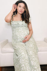woman wearing a green floral maternity maxi dress and holding her baby bump