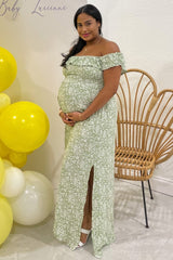 woman wearing a green floral off-shoulder maternity gown with a thigh slit and a visible baby bump