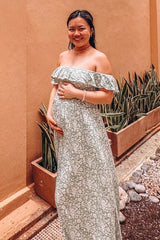 woman wearing a green floral off-shoulder maternity maxi dress with a visible baby bump