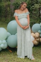 woman wearing a light green off-the-shoulder maternity dress, holding her baby bump in a garden setting with balloons