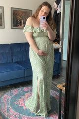 woman wearing a green off-shoulder maternity dress with a thigh-high slit and holding her baby bump