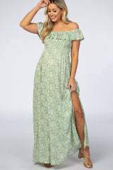 woman wearing a green floral off-the-shoulder maternity maxi dress with a thigh-high slit
