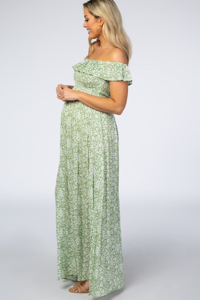woman wearing a green floral off-the-shoulder maternity maxi dress and showing her baby bump