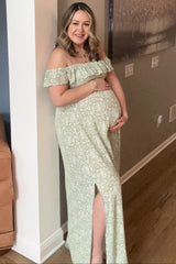 smiling pregnant woman in a green floral off-the-shoulder maternity dress holding her baby bump