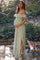 Pregnant woman in green floral off-the-shoulder maternity maxi dress posing outdoors near a park bench