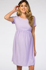woman wearing a light purple short sleeve maternity dress with textured fabric and an empire waist accommodating a baby bump