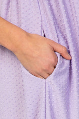 maternity wear light purple dress with textured pattern and side pocket, model holding pocket with one hand