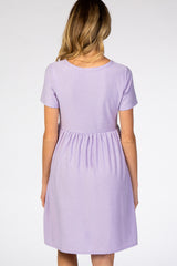 woman wearing a lavender short sleeve maternity dress with a textured dot pattern and a gathered waistline