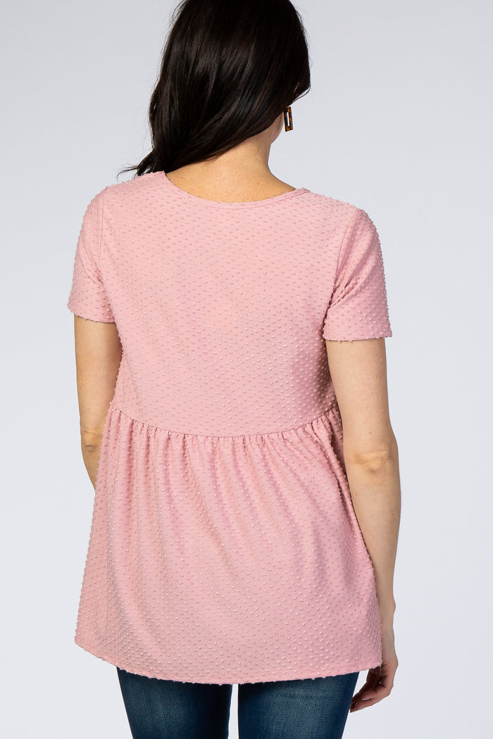 woman wearing a pink short sleeve peplum top with a textured design and a relaxed fit, viewed from the back
