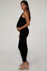 woman wearing a black one-shoulder maternity dress and holding her baby bump