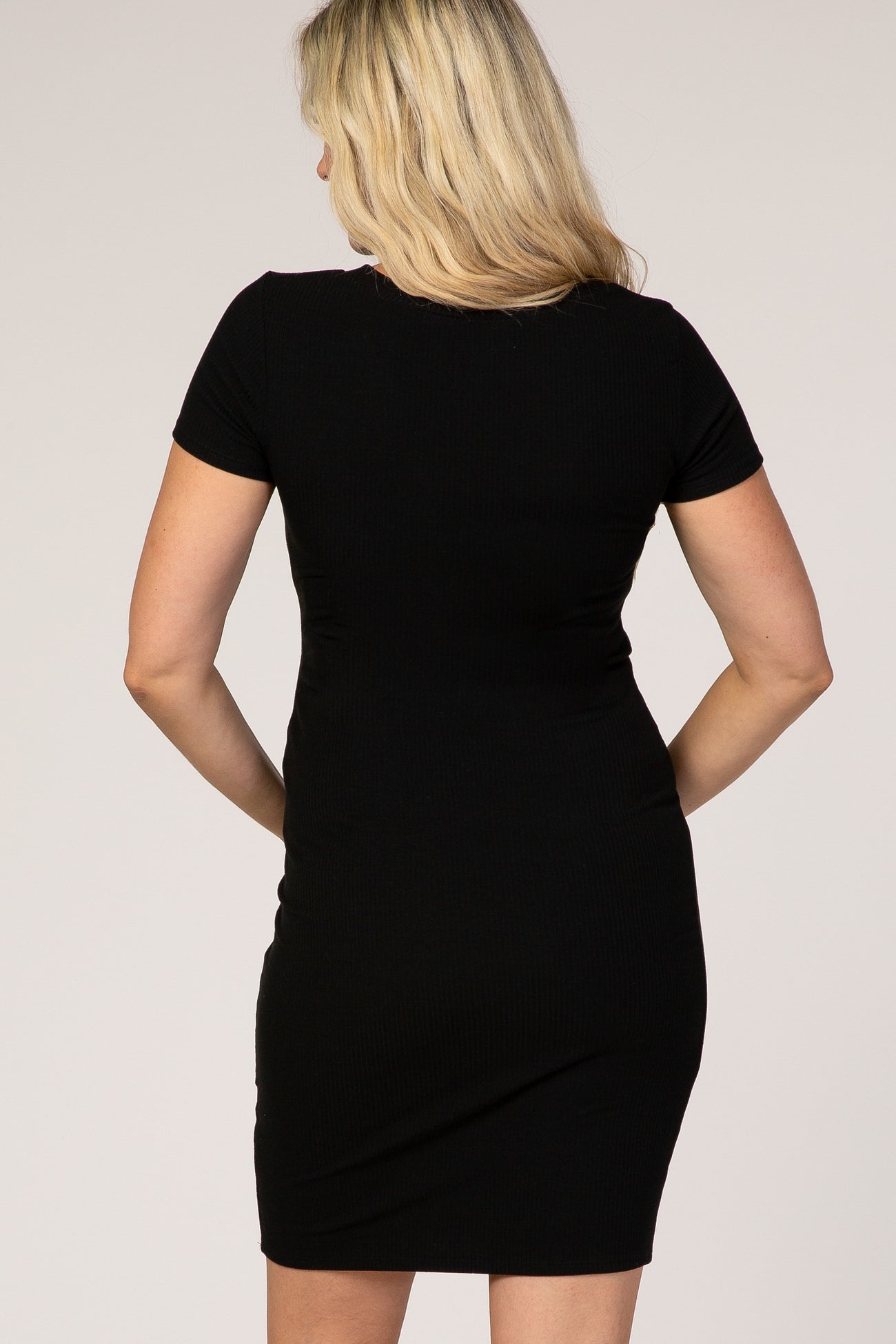 woman wearing a black short sleeve ribbed maternity dress, showing the back view